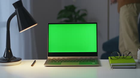 person-finished-work-in-home-office-is-turning-off-lights-in-room-and-closing-laptop-with-green-screen-closeup-on-working-table-place-for-remote-work-in-apartment